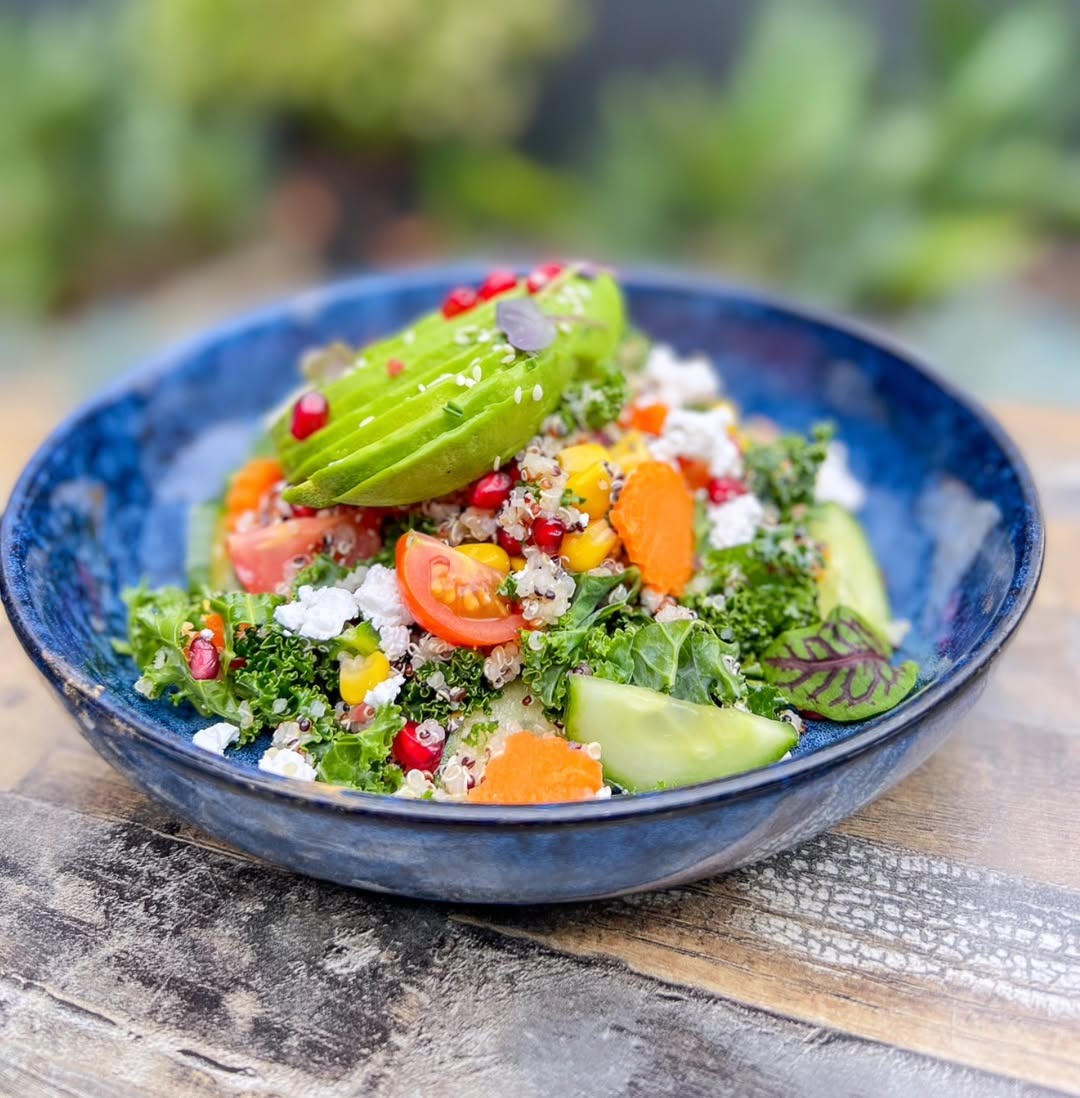 Kale and quinoa salad bowl with avocado, feta and pomegranate