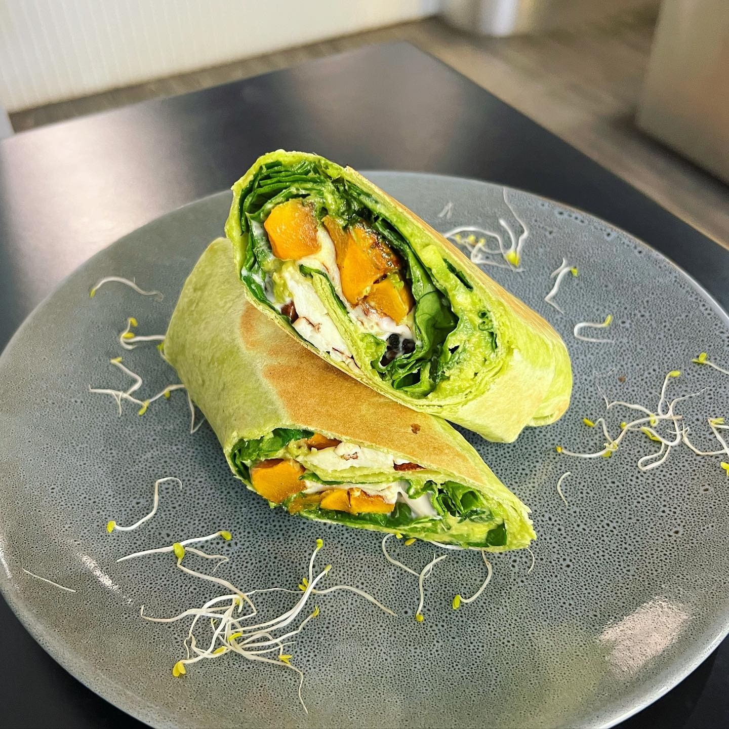 Roast pumpkin, spinach and feta wrap sliced on a stone plate